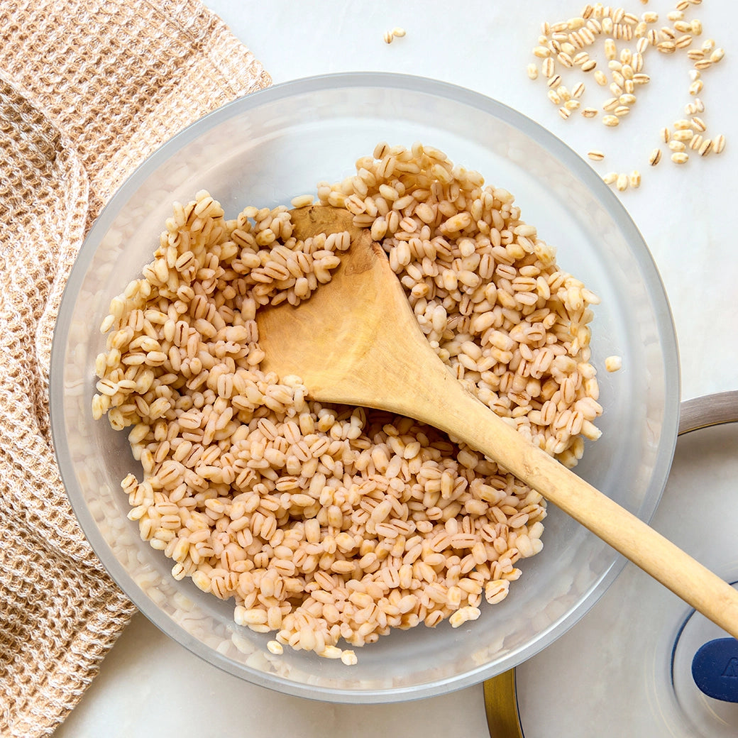 Cooked quick barley in a clear Anyday dish with a spoon and visible grains