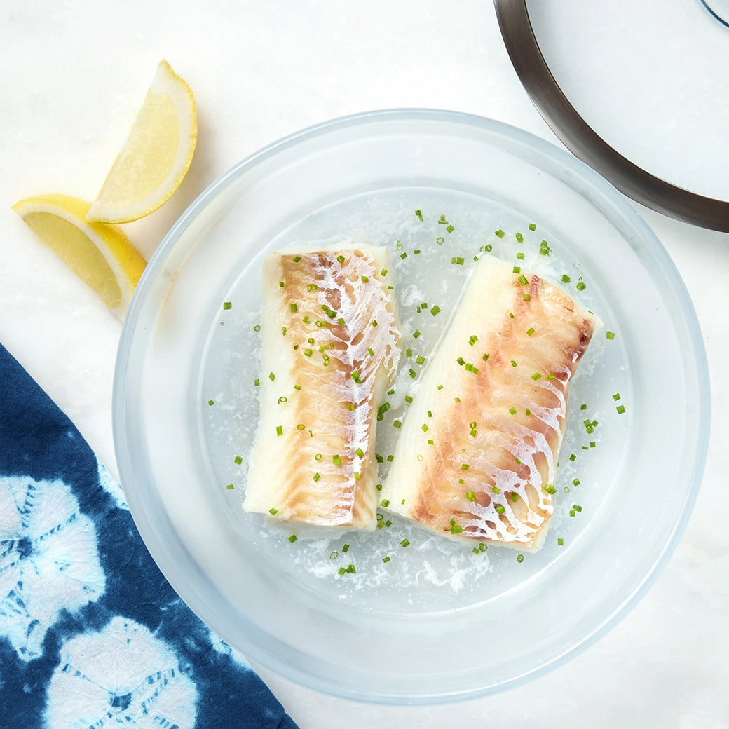 Cooked cod fillet in a clear Anyday dish with a fork and a light garnish