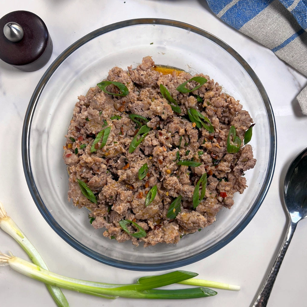 Cooked ground pork in a clear Anyday dish, broken into crumbles with lid to the side