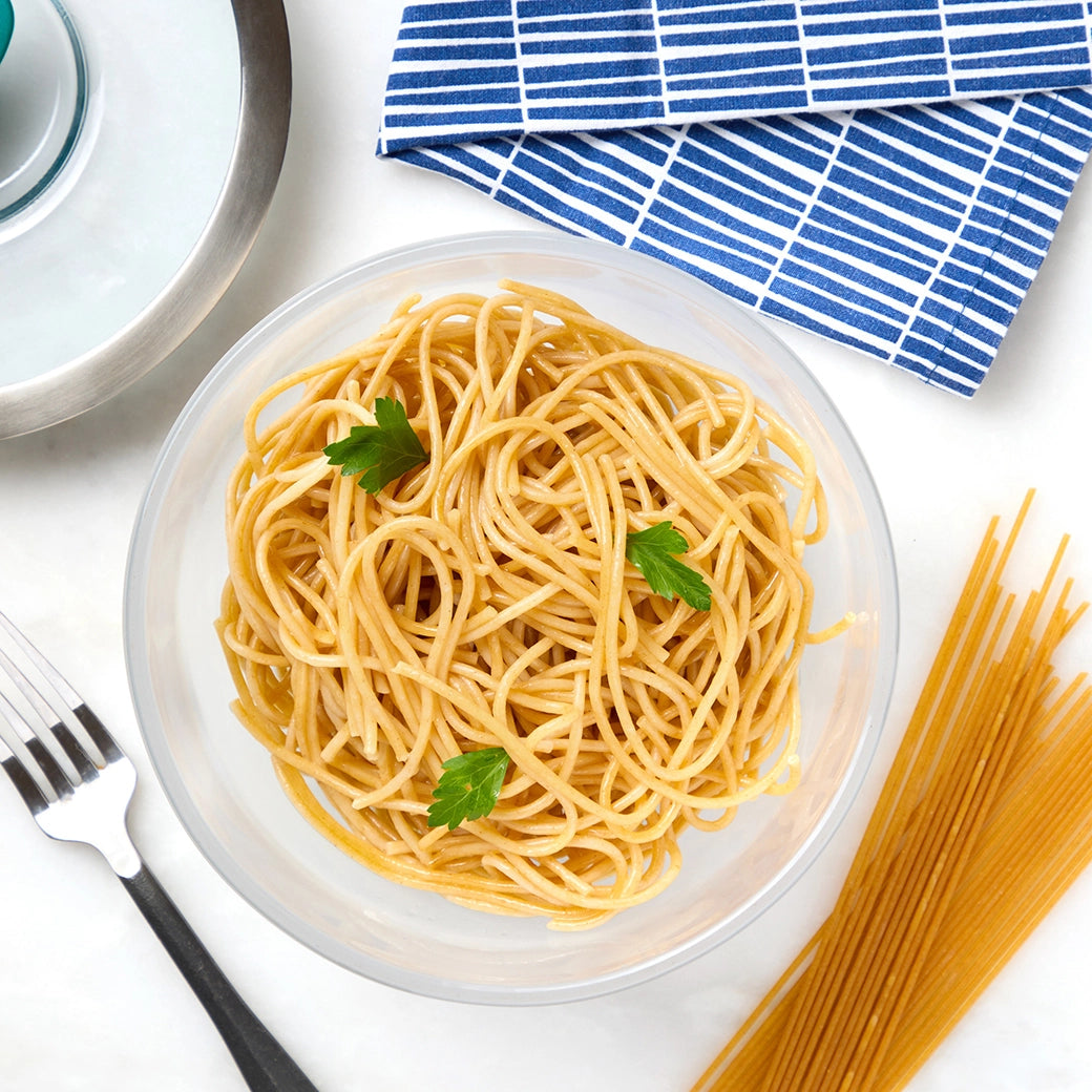 Cooked spaghetti noodles in a clear Anyday dish with visible sauce and fork nearby