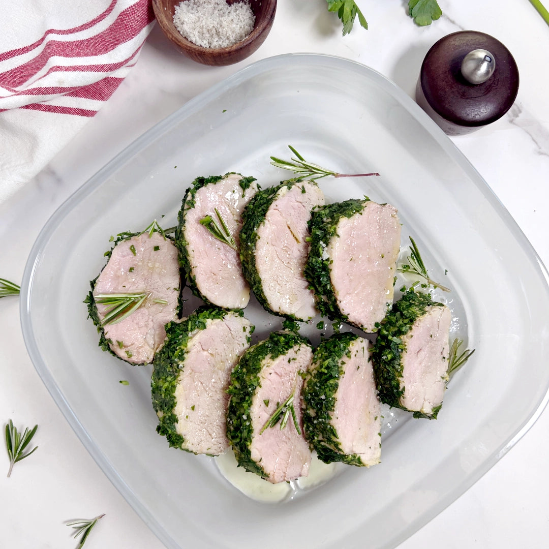 Pork tenderloin cooked in an Anyday dish, coated with fresh herbs and garnished with rosemary sprigs.