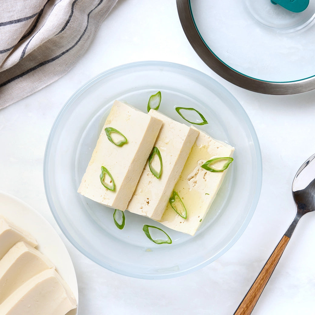 Cubed tofu in a clear Anyday dish on a neutral background, lightly steamed