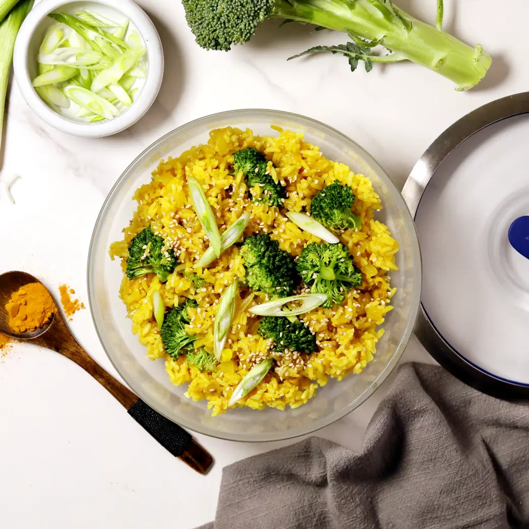 A close-up of golden fried rice served in an Anyday dish, showing fluffy rice with turmeric, chopped vegetables, and creamy egg yolk stirred in.