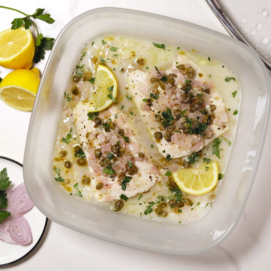 A piece of flaky sole in an Anyday dish, topped with melted butter, lemon slices, and capers for a quick, elegant meal cooked in the microwave.