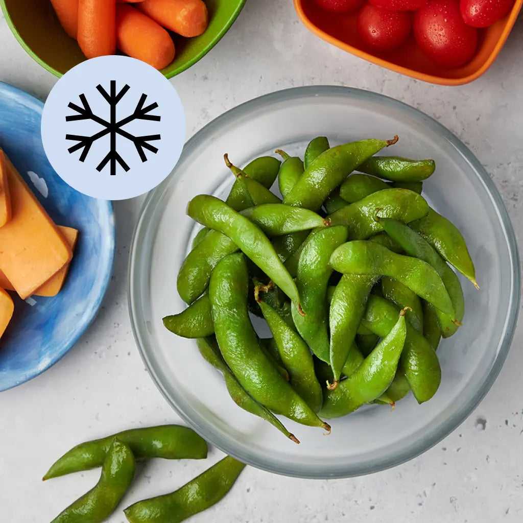 Frozen edamame pods in a clear Anyday dish on a light surface with lid nearby