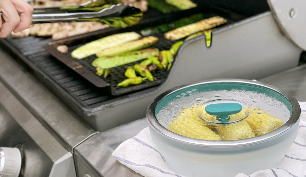 Anyday microwave cookware with corn on the cob next to a grill with food