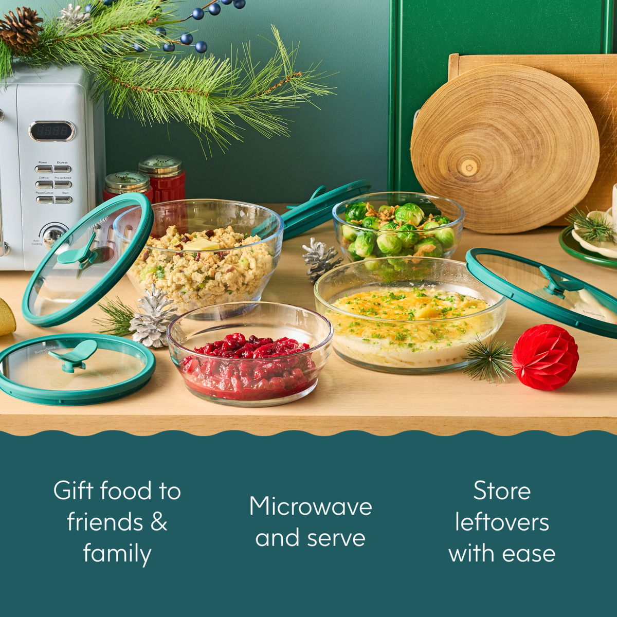 Four Steph’s Must-Haves (kale) glass dishes with glass lids containing cooked food and cranberries on a wooden surface, with text reading Gift food to friends & family, Microwave and serve, Store leftovers with ease.