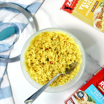 Flavored boxed yellow rice cooked in an Anyday dish, served with a spoon, with the lid and packaging visible nearby
