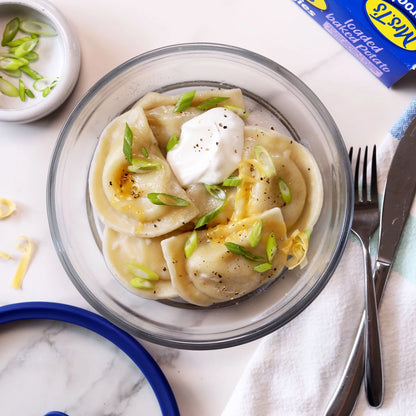 Microwave frozen pirogis with spur cream, salt and pepper in an Anyday glass dish, with scallions on the side