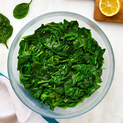 Fresh spinach leaves cooked down in a clear Anyday dish with lid off to the side

