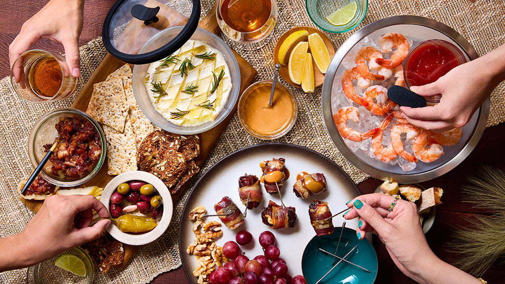 Diverse food platter with shrimp, fruits, and other snacks on a table.