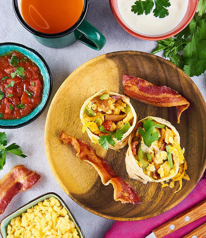 Bacon, egg, and cheese burrito made in a glass Anyday dish, garnished with fresh parsley and accompanied by salsa, sour cream, and a hot drink.