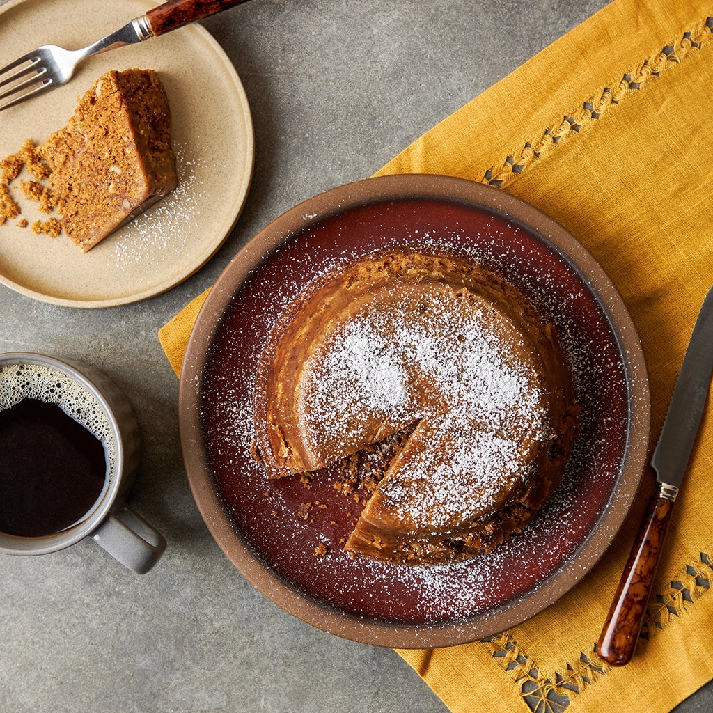 Delicious banana bread dusted with powdered sugar, made in a glass Anyday and served with a cup of coffee.