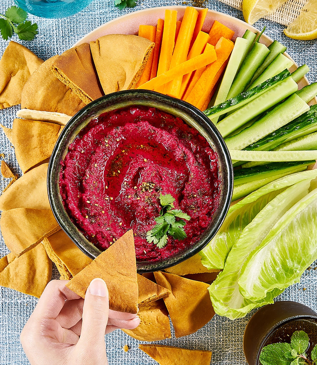 Beet hummus made in a glass Anyday dish, served in a bowl, with pita bread, and fresh vegetables