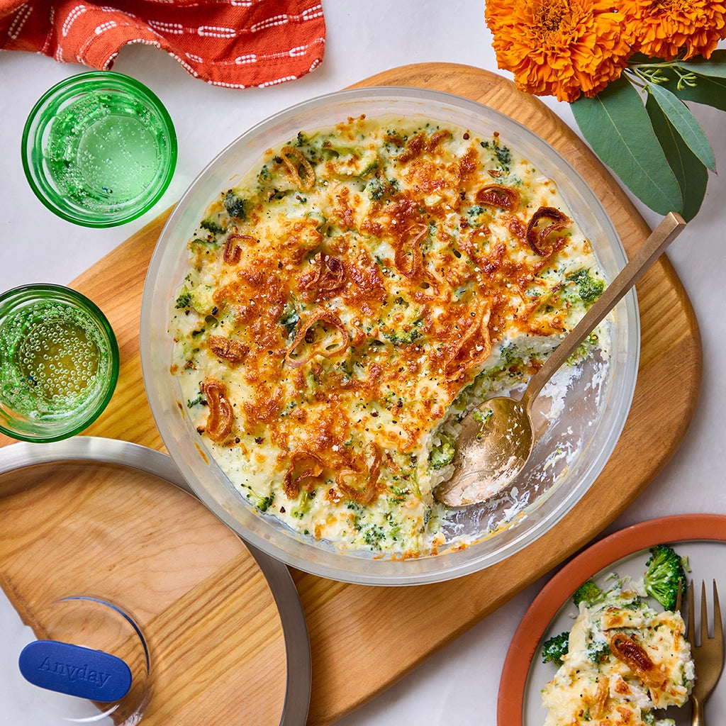 Broccoli cheese casserole with a golden-brown top, made and served in a clear glass Anyday dish.