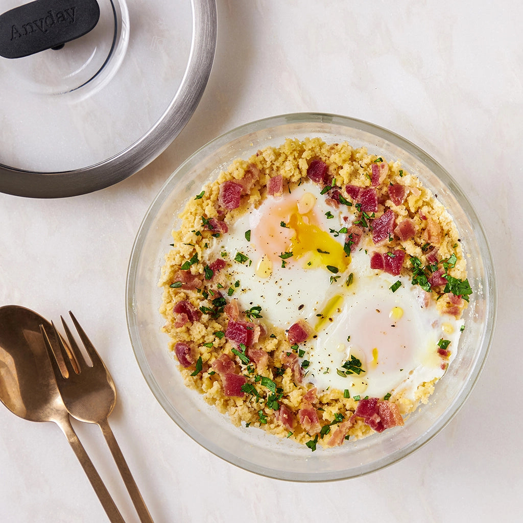 ChihYu Smith's Paleo Breakfast Grits made and served in the glass Anyday dish, featuring creamy grits topped with a poached egg and fresh herbs.