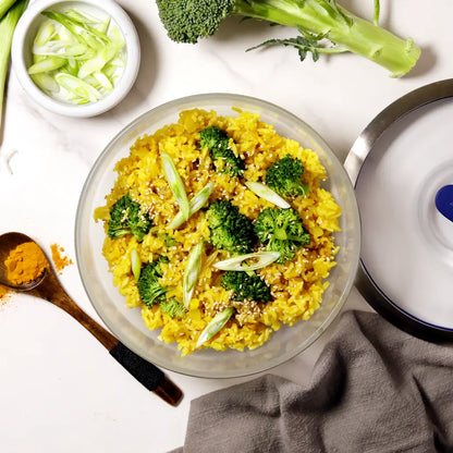 A close-up of golden fried rice served in an Anyday dish, showing fluffy rice with turmeric, chopped vegetables, and creamy egg yolk stirred in.