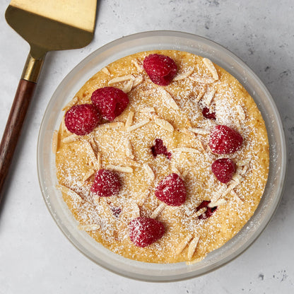 Grapefruit and Almond Yogurt Cake made and served in the glass Anyday dish, featuring a moist, flavorful cake with hints of grapefruit, fresh raspberries and almond.