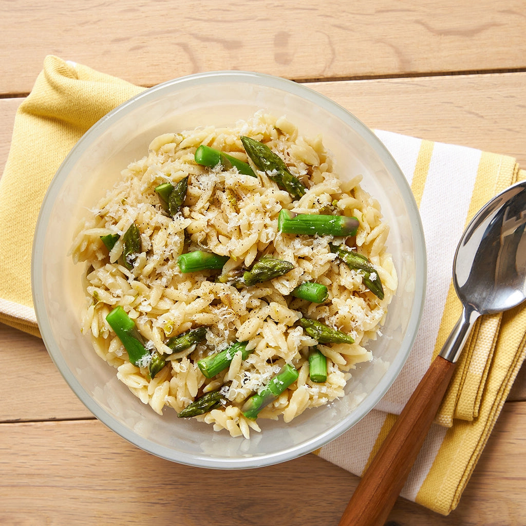 Perfectly cooked Lemon Orzo with Asparagus made and served in the glass Anyday dish, providing tender orzo and crisp asparagus with a hint of lemon. This method ensures evenly cooked pasta without the need to pre-boil the water, ideal for a refreshing and delicious meal."