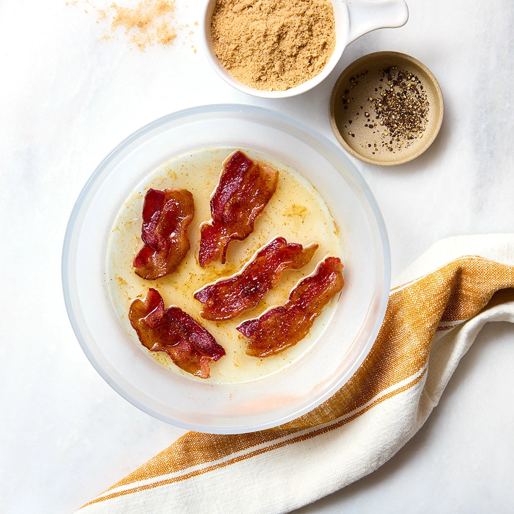 Deliciously crispy Millionaire's Bacon made in the glass Anyday dish, featuring thick-cut bacon coated in brown sugar, black pepper, and cayenne. This quick and easy method ensures perfectly caramelized bacon strips with a sweet and spicy kick and no splatter, ideal for breakfast or brunch.