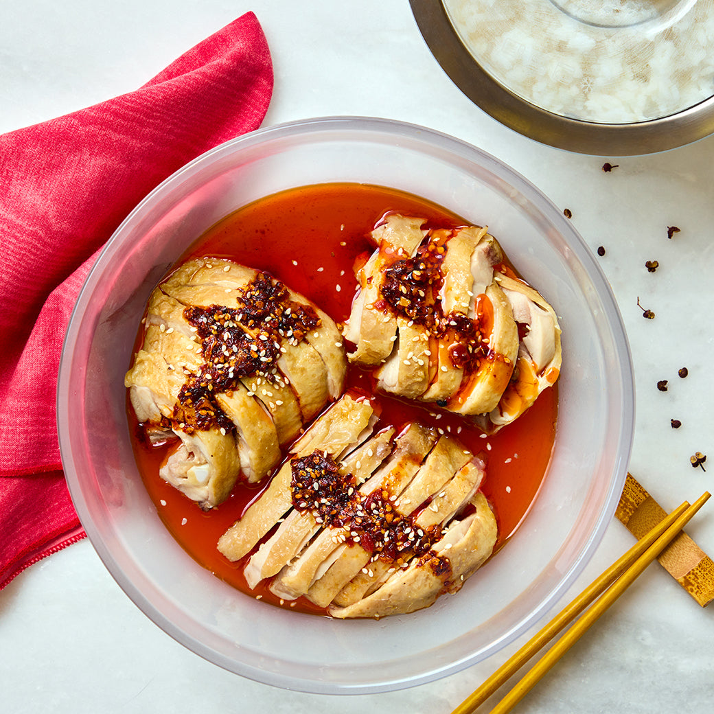 Delicious Sichuan chicken served in a clear glass Anyday dish, garnished with green onions and sesame seeds.