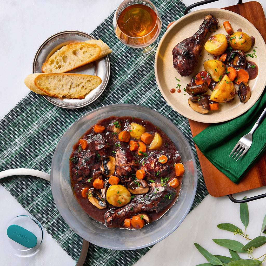 Flavorful Coq au Vin with chicken drumsticks, root vegetables, and rich red wine sauce, served in a clear glass Anyday dish.