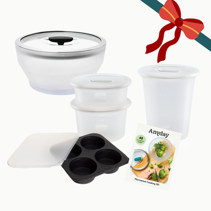 The Anyday Starter Gift Bundle (black) includes a large glass dish, two small silicone containers, one tall silicone container, a black silicone muffin tray with a cover, and a recipe booklet.