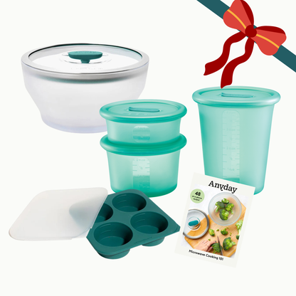 An Anyday The Starter Gift Bundle (kale) featuring a glass bowl with a glass lid, two stackable silicone containers, a four-cup silicone tray with a silicone cover, and a recipe booklet, all tied with a decorative bow.