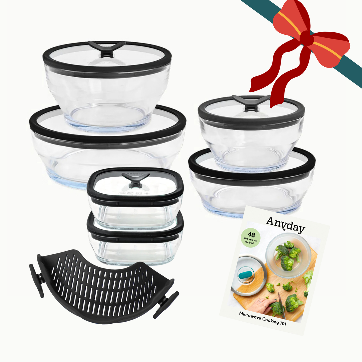 Steph’s Must-Haves (black) clear glass food storage containers with black glass lids, a black slotted silicone insert, and a recipe booklet, decorated with a festive red gift bow.
